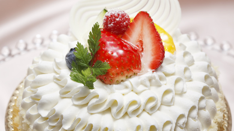 Cake covered in whipped cream with fruit on top