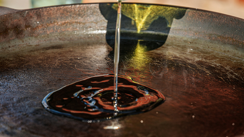 a close up of pouring olive oil in skillet