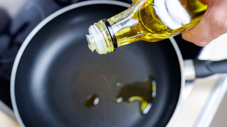 top view image of a person pouring olive oil in pan