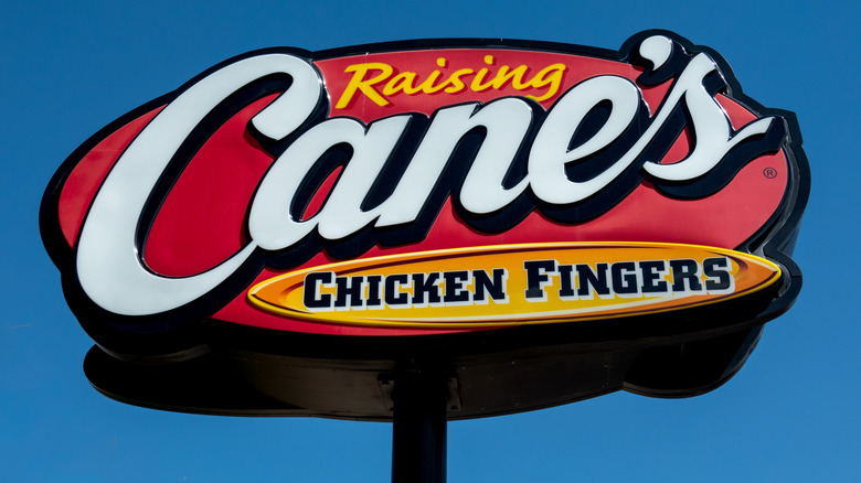 A Raising Canes sign against a blue sky
