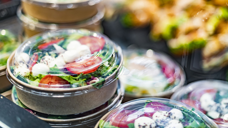 Round containers of prepared salads in refrigerated section