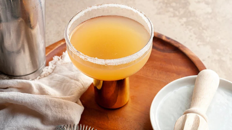 Sidecar with sugar rim on wooden tray next to bar tools