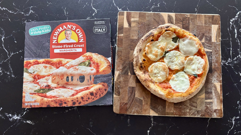 Newman's Own margherita pizza box next to margherita pizza on wooden board