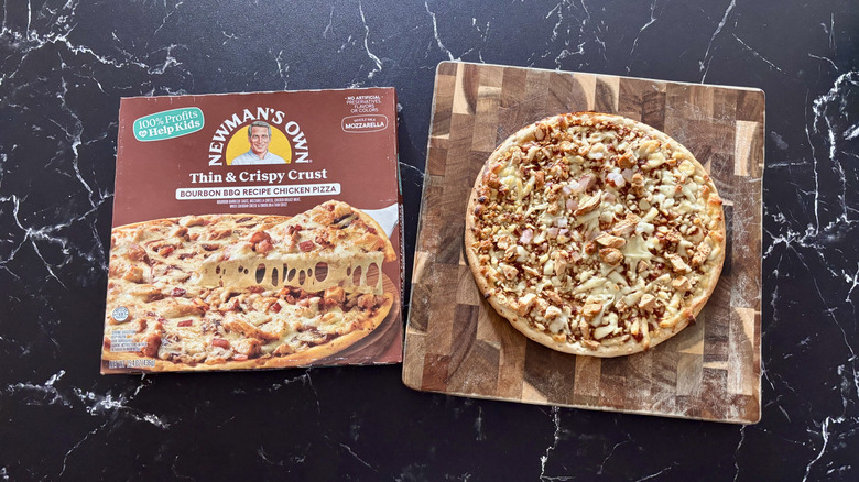 Newman's Own bourbon BBQ chicken pizza box next to BBQ chicken pizza on wooden board