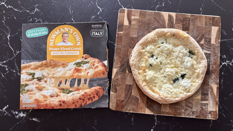 Newman's Own quattro formaggi pizza box next to cheese pizza on wooden board