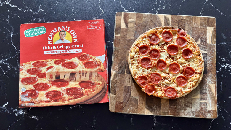 Newman's Own pepperoni pizza box next to pepperoni pizza on wooden board