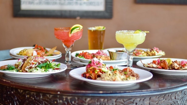 Various Mexican dishes and bright cocktails on a table