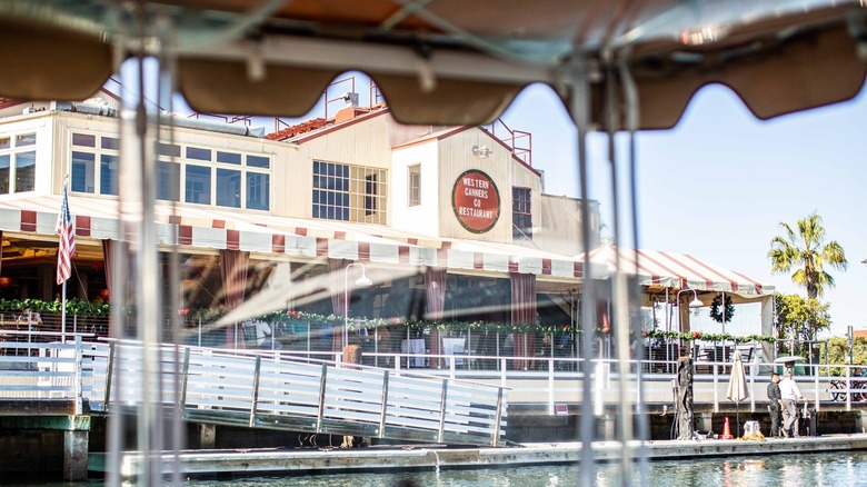A photograph of the waterfront exterior of The Cannery restaurant taken through a boat awning