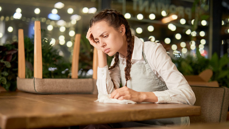 Sad person sitting at an empty table in restaurant