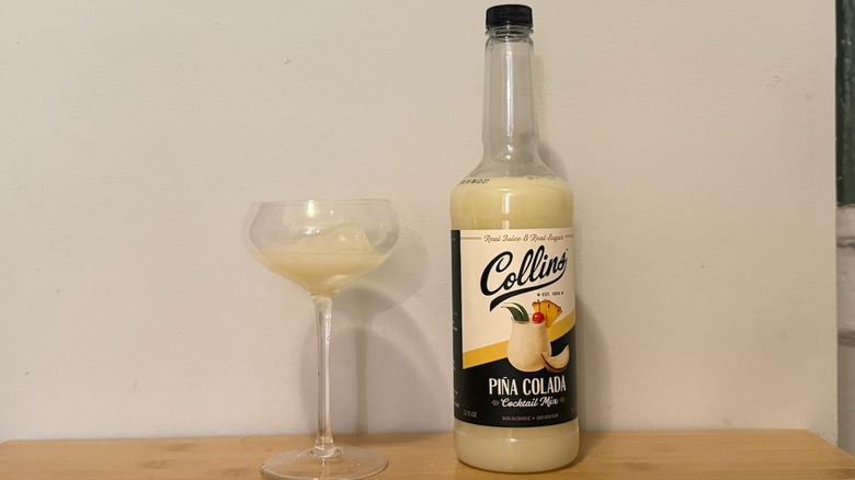bottle of Collins piña colada mixer with a filled glass next to it