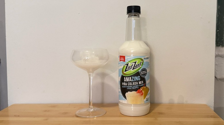 bottle of Zing Zang piña colada mix with glass filled next to it