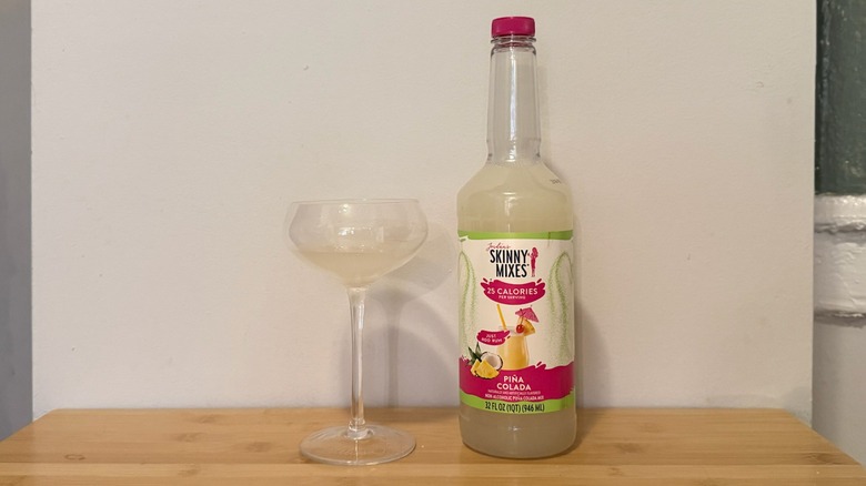 Skinny Mixes piña colada bottle with a glass filled next to it
