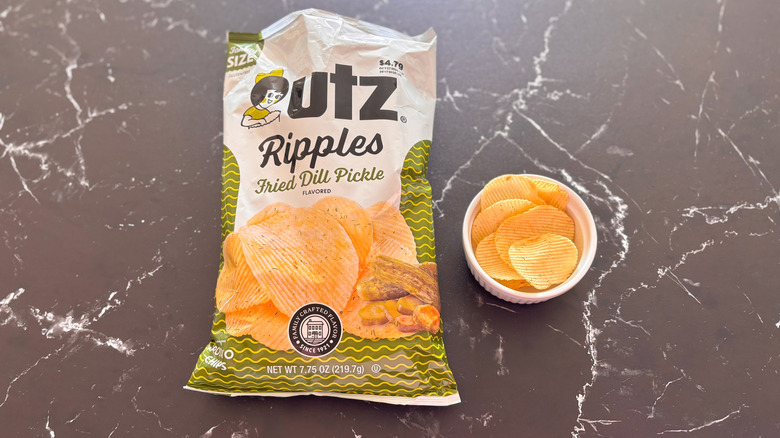 Bag of Utz fried dill pickle potato chips next to bowl of chips