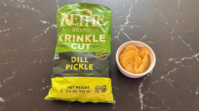 Kettle brand dill pickle crinkle cut chips next to bowl of chips