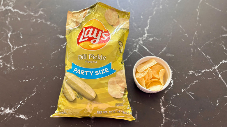 Bag of Lay's dill pickle chips next to bowl of chips