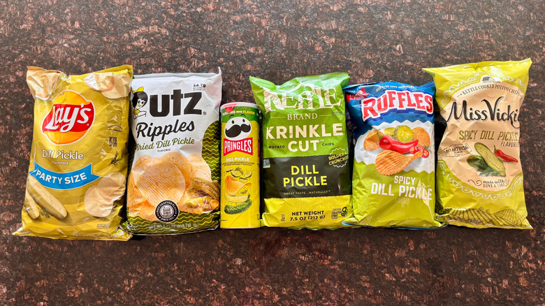 Various dill pickle-flavored potato chip bags on countertop