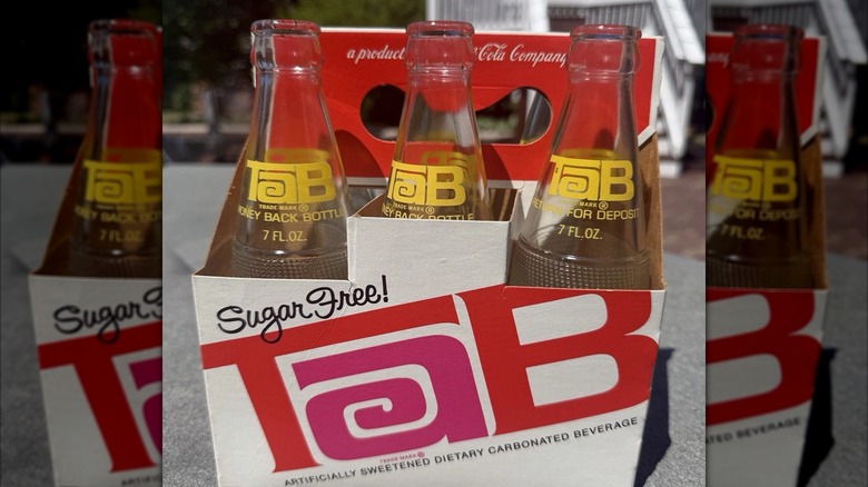 Mirrored image of TAB Soda six pack carrier with glass bottles