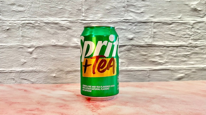 Sprite + Tea can on pink marble surface