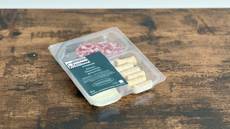 Wooden table with plastic container of Starbucks Artisan Charcuterie Box