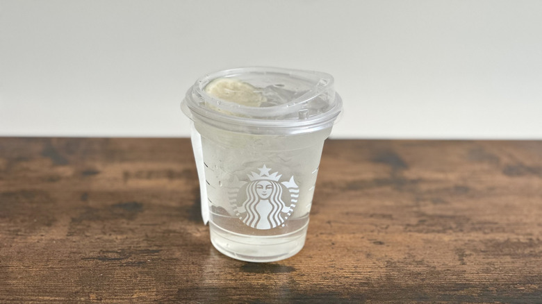 Wooden table with plastic cup of Starbucks Cool Lime Refresher drink