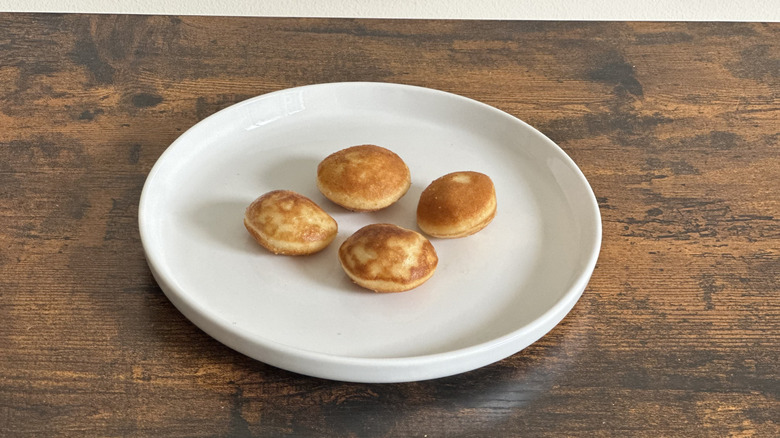 Wooden table with white plate with four small pancakes
