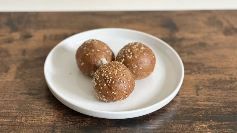 Wooden table with white plate with three rye bagel balls