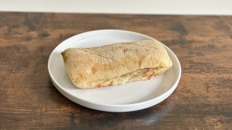 Wooden table with white plate with turkey sandwich on ciabatta