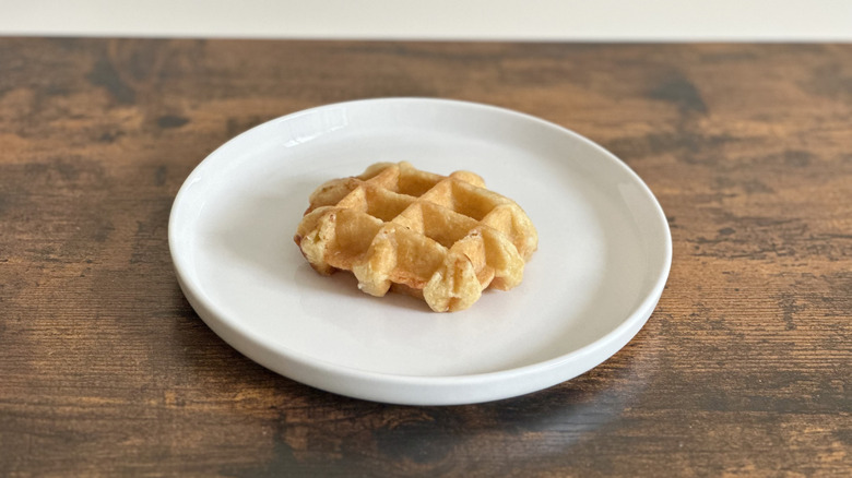 Wooden table with white plate with Belgian waffle on it