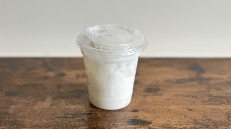 Wooden table with plastic cup of Starbucks Lime Coconut Drink