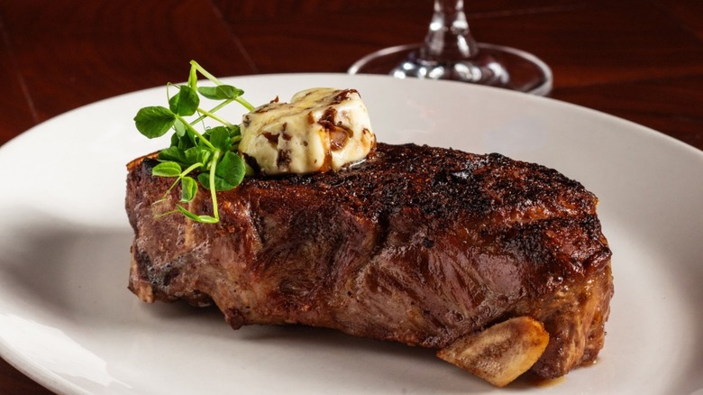 KC Strip on white plate with roasted mushroom butter and greenery