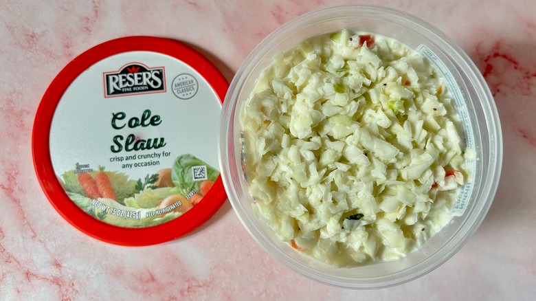 Reser's coleslaw container next to lid on pink surface