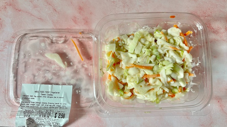 Whole Foods coleslaw container next to lid on pink surface