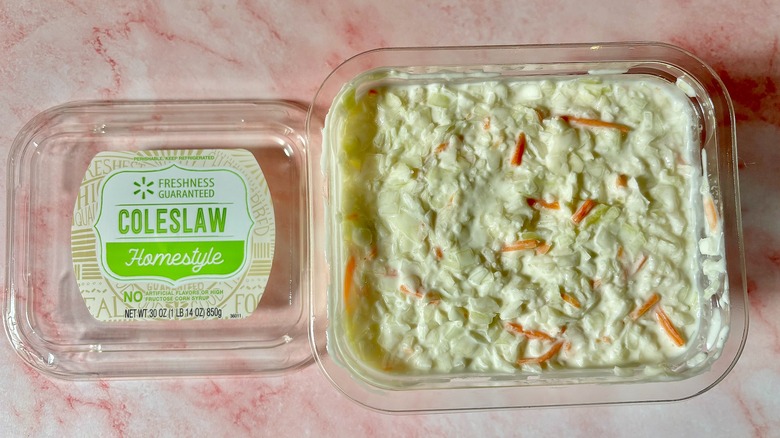 Freshness Guaranteed coleslaw container next to lid on pink surface