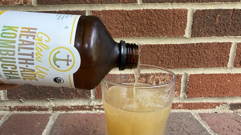 Ginger-flavored kombucha being poured into glass from Health-Ade bottle