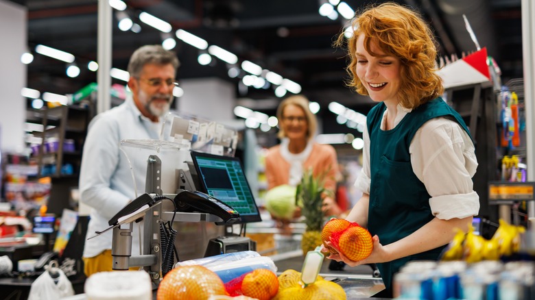 Woman scanning bag of oranges in checkout line
