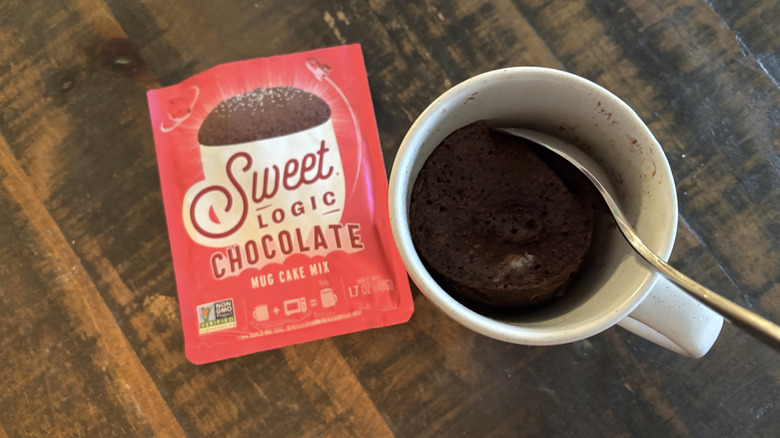 Sweet Logic chocolate mug cake in package and mug on wooden table.