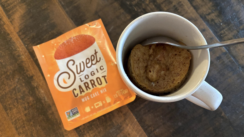 Sweet Logic carrot mug cake in package and mug on wooden table.