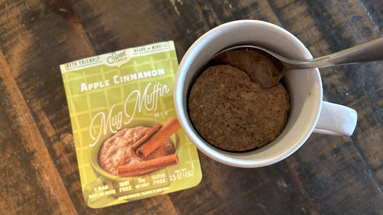 Sweet Logic apple cinnamon mug cake in package and mug on wooden table.