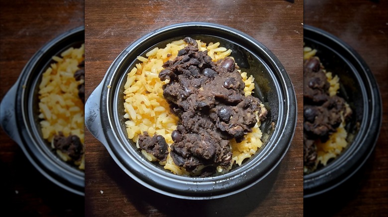 Black beans and rice in a black container on a table, mirrored image
