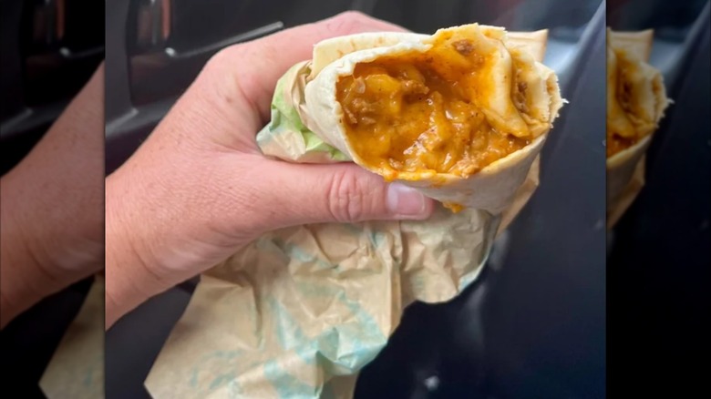 Mirrored image of hand holding chili cheese burrito