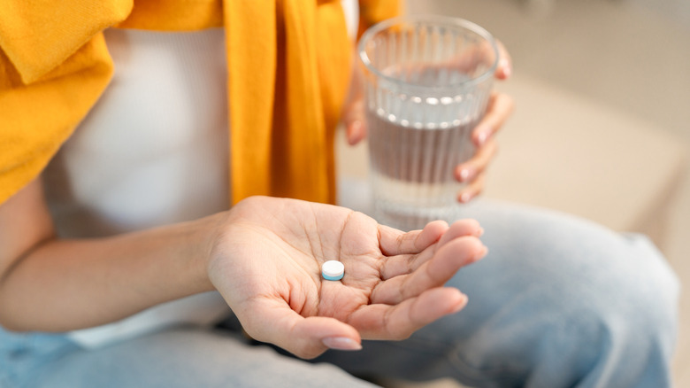 Person holding an aspirin and water
