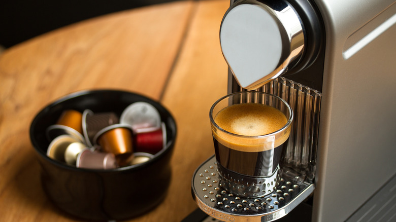 A Nespresso machine next to a bowl of coffee pods