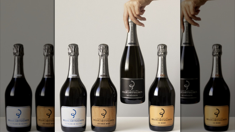 four bottles of champagne and hand reaching for one