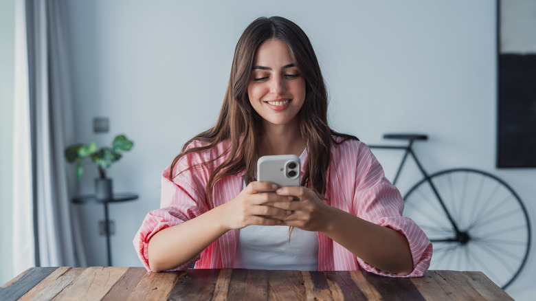 Woman sitting at table using cell phone