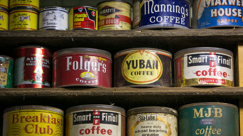 Vintage coffee cans stacked on wooden shelves