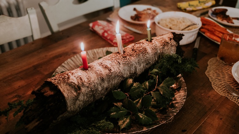 Yule log on table with three candles burning