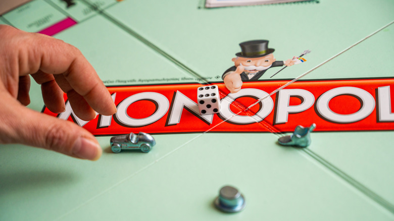 Hand picking up car on Monopoly board