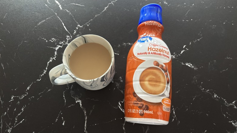 Cup of coffee next to Great Value hazelnut coffee creamer bottle