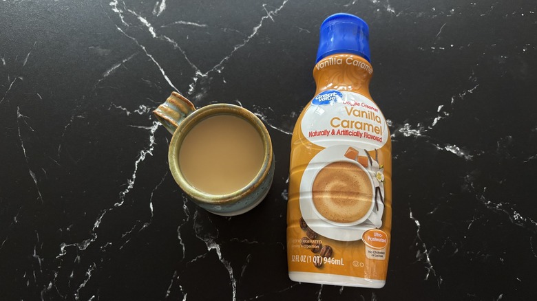 Cup of coffee next to Great Value vanilla caramel creamer bottle