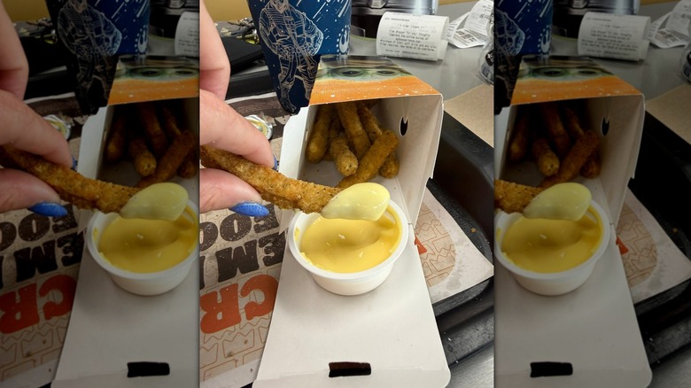 Hand dipping Burger King chicken fry into sauce
